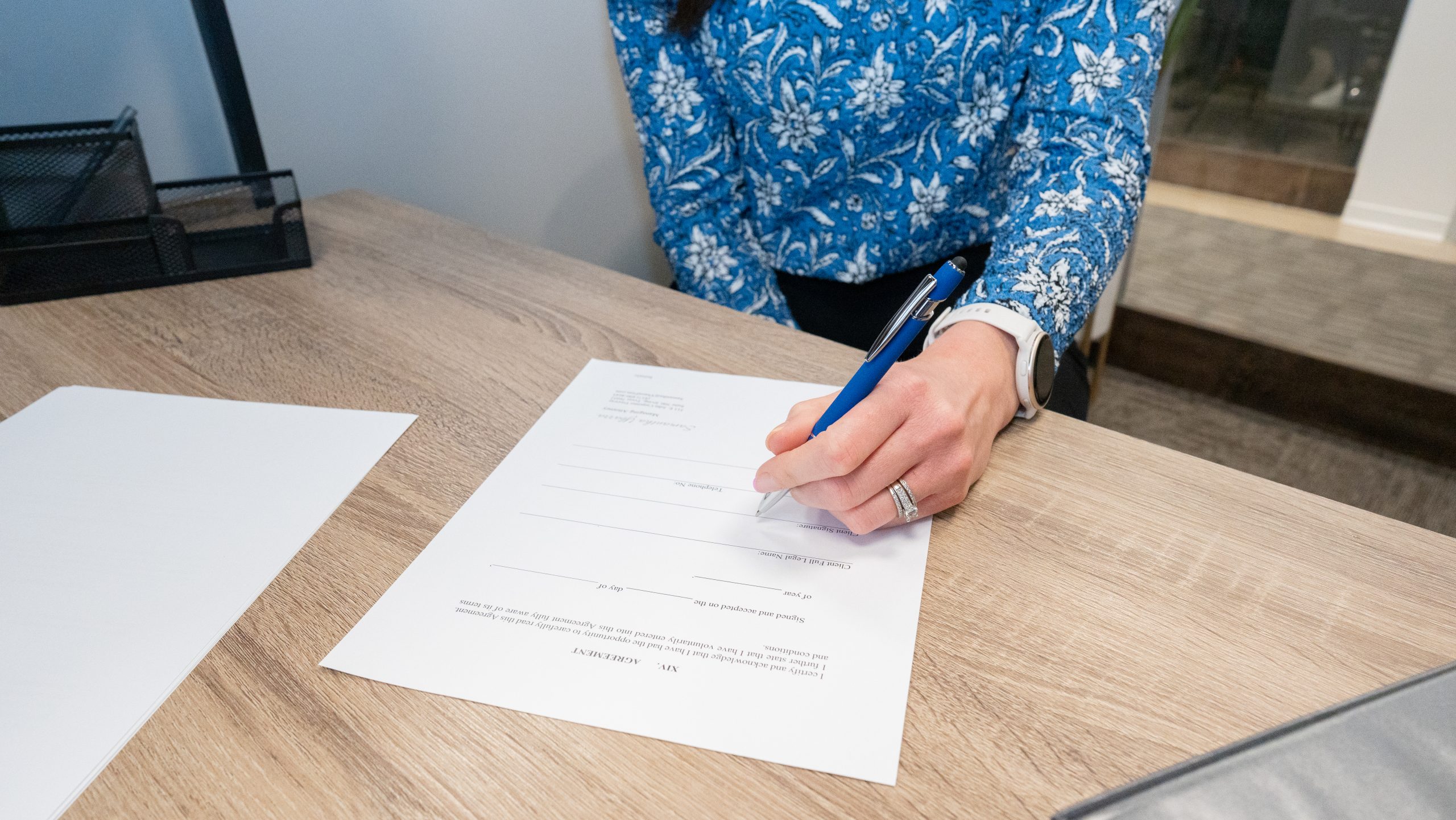 Client signing legal agreement on a wooden desk at Ybarra Law Firm